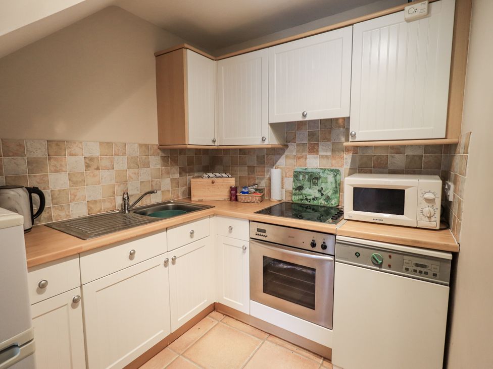A kitchen with appliances and cabinets at Millers Cottage Seaville near Wigton
