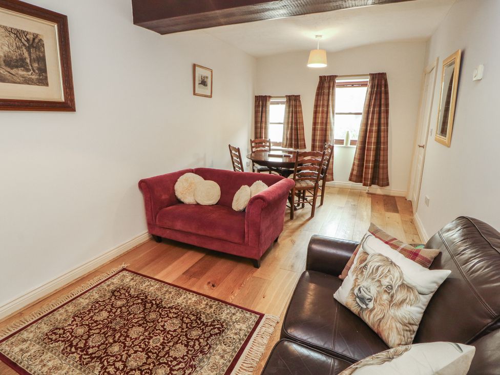 A living room with a sofa and dining table at Millers Cottage in Seaville near Wigton