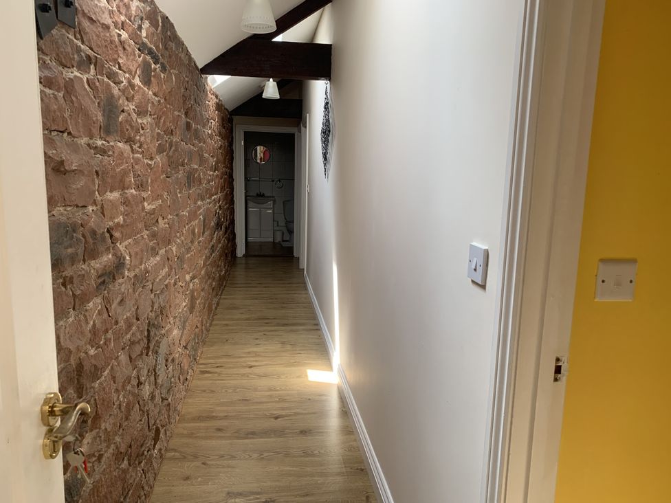 A corridor with a brick wall and wooden floor at The Hayloft near Wigton