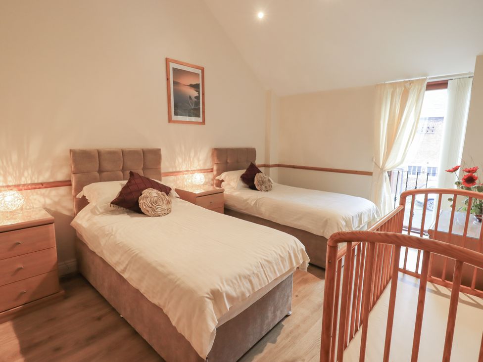 A bedroom with two single beds and a crib at The Hayloft near Wigton