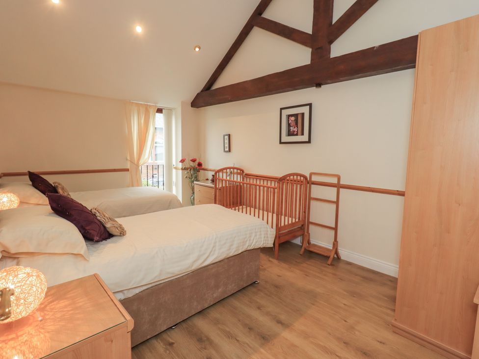 A bedroom with two beds and a crib at The Hayloft near Wigton