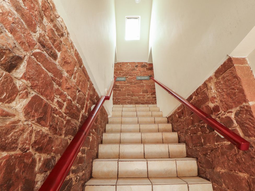 A staircase with stone walls and signage at The Hayloft near Wigton