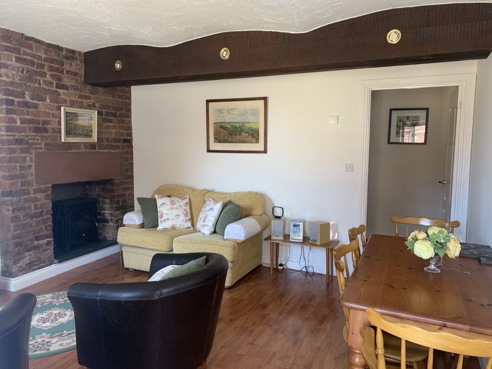 A living room with a sofa and a dining table at The Coach House near Wigton