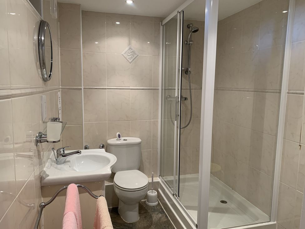 A bathroom with a shower, washbasin, and toilet at The Coach House near Wigton