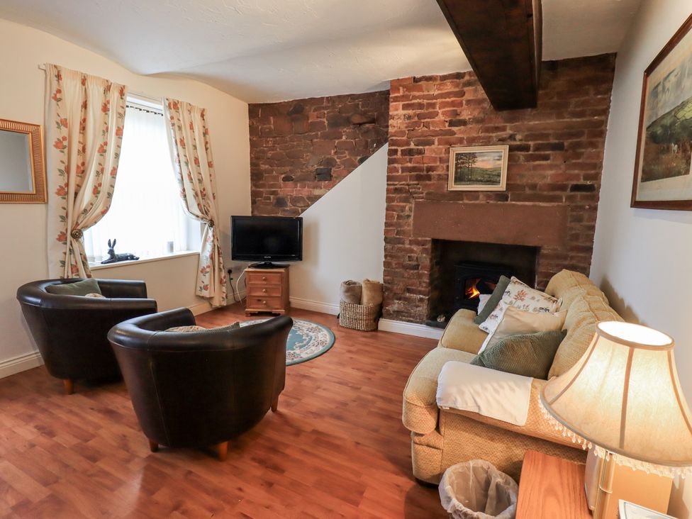 A living room with a fireplace and furniture at The Coach House near Wigton
