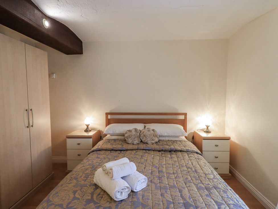 A bedroom with a bed, wardrobe, and nightstands at The Coach House near Wigton