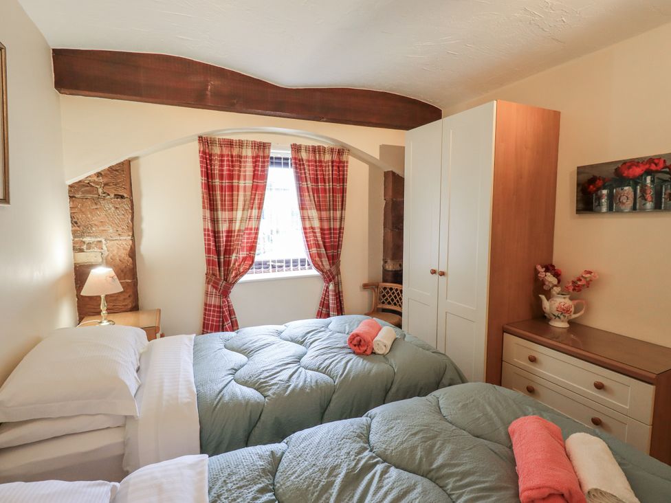 A bedroom with two beds and curtains at The Coach House near Wigton