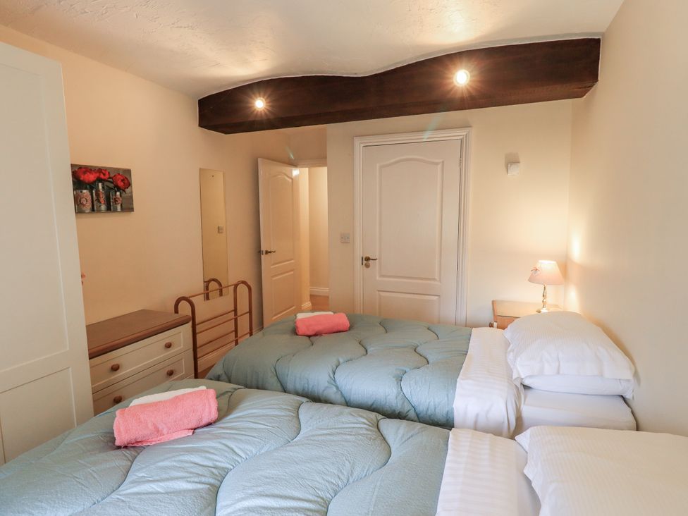 A bedroom with two beds and a lamp at The Coach House near Wigton