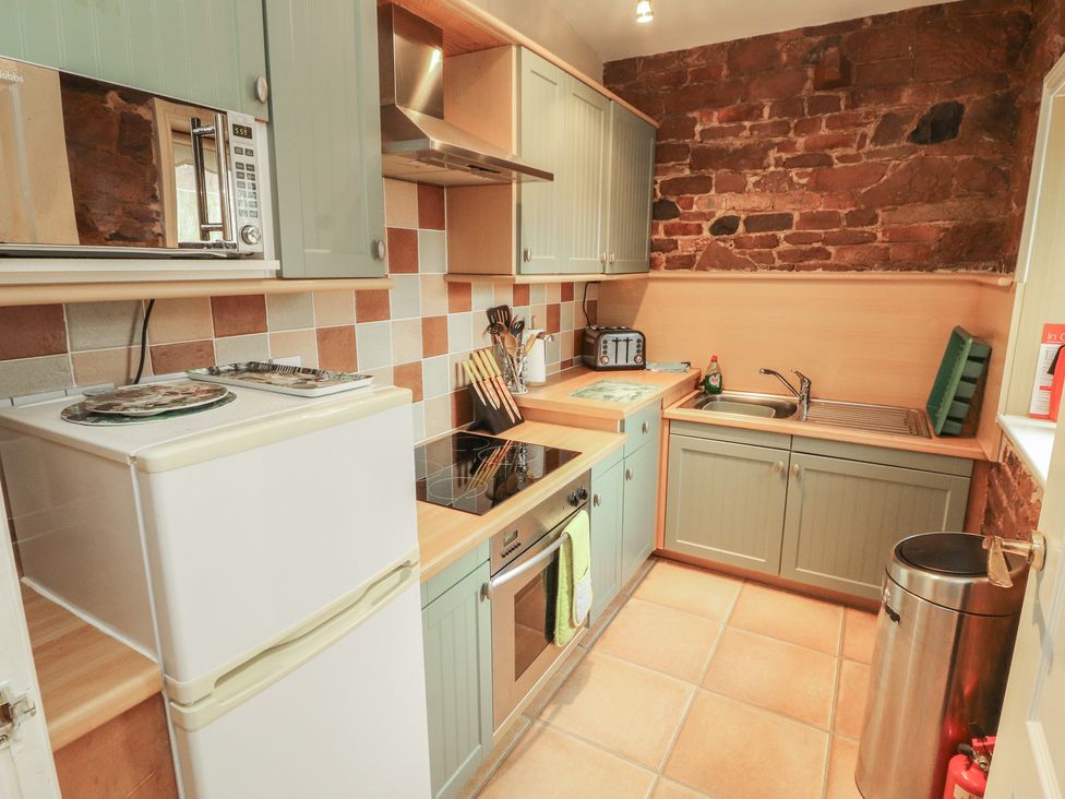 A kitchen with appliances and wooden cabinetry at The Coach House near Wigton