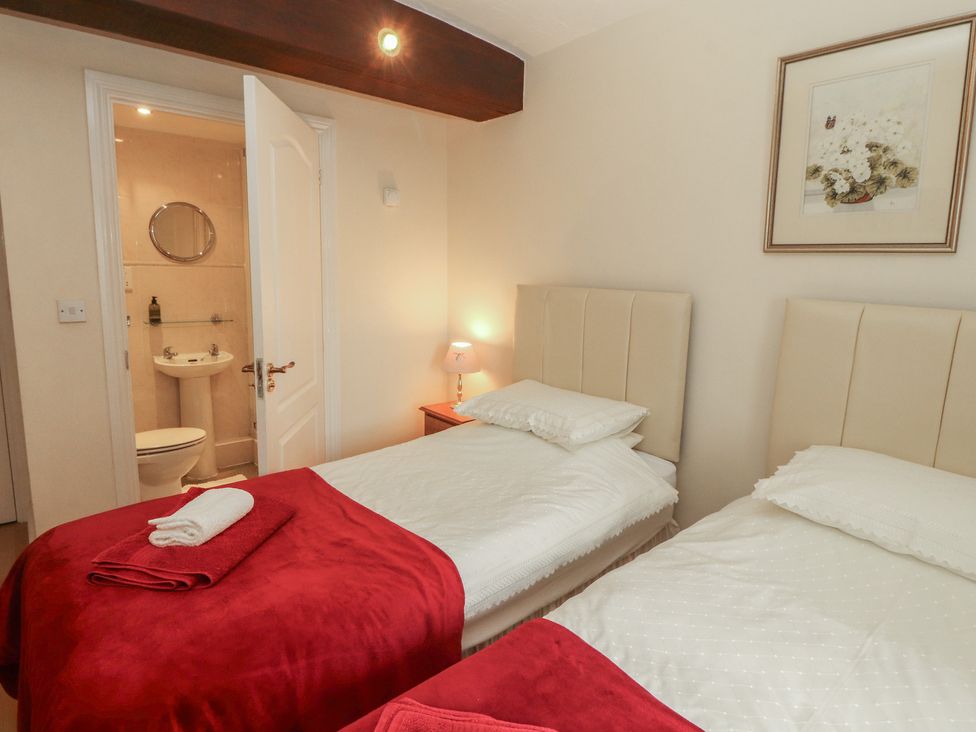 A bedroom with two beds and an ensuite bathroom at The Coach House near Wigton