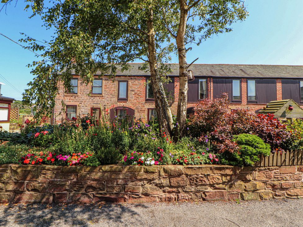 A building with a flower bed and tree at The Coach House near Wigton