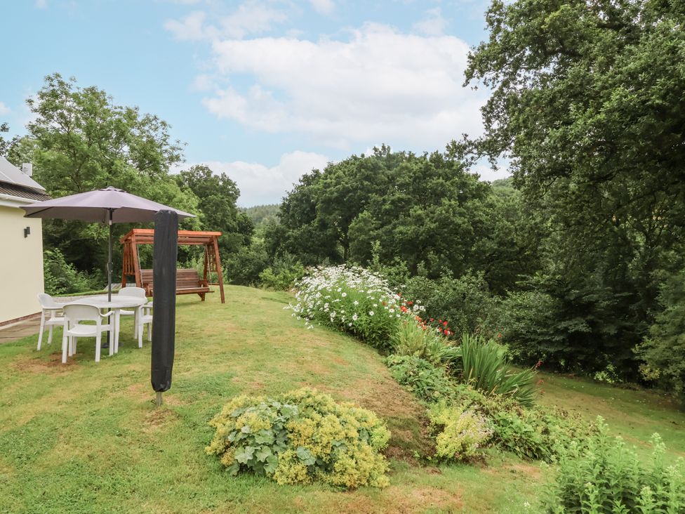 A garden with a table and chairs and a swing at Hideaway in Great Torrington