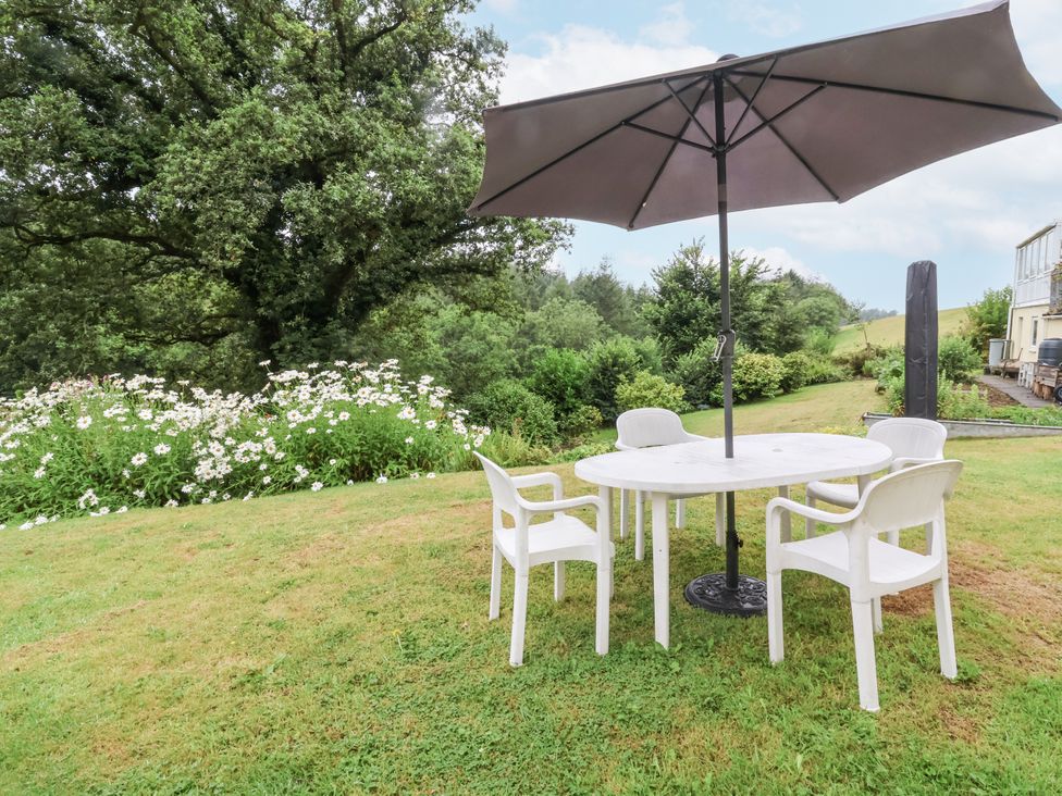 A table with chairs and an umbrella in a garden at Hideaway in Great Torrington