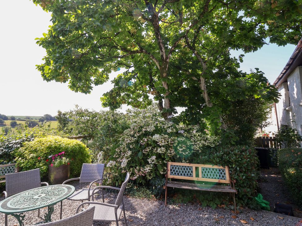 A garden with a table and chairs under a tree at Magnolia View in Goodleigh near Barnstaple
