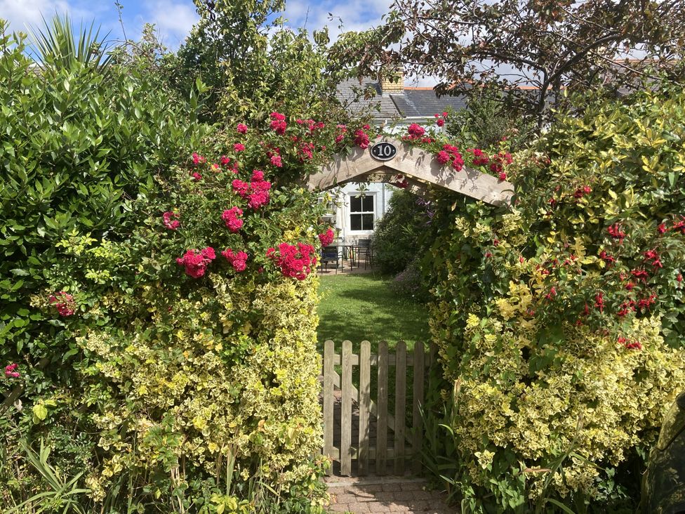 A garden entrance with flowers and a wooden gate at 5 Bed Cottage Mumbles