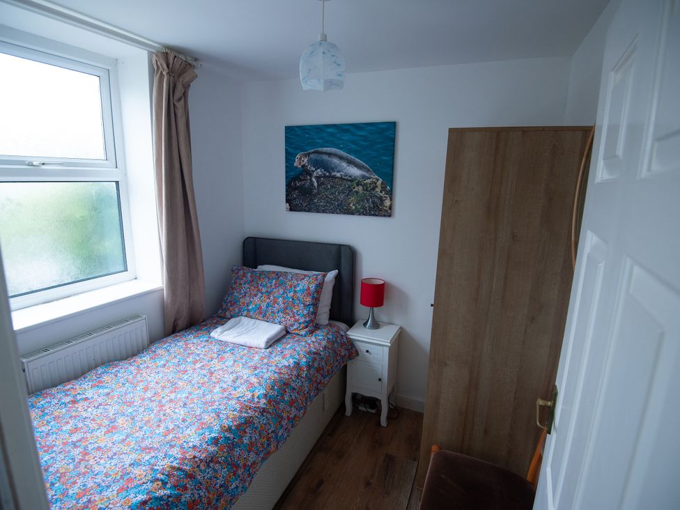 A bedroom with a bed and nightstand at 5 Bed Cottage Mumbles