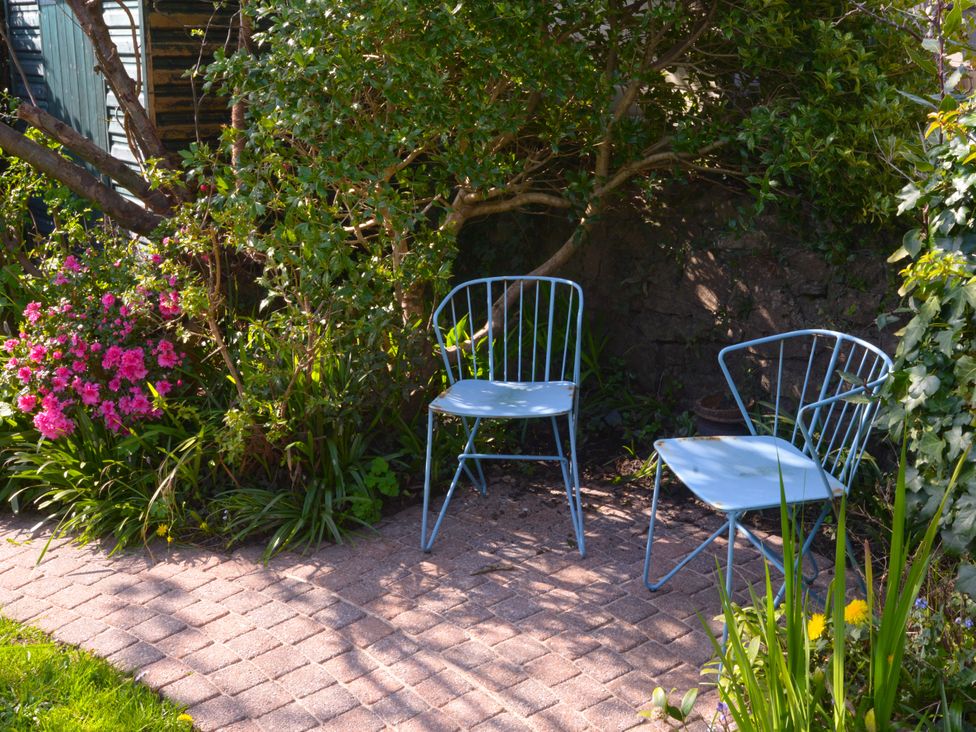 Two blue chairs beside flowers in a garden at 5 Bed Cottage Mumbles