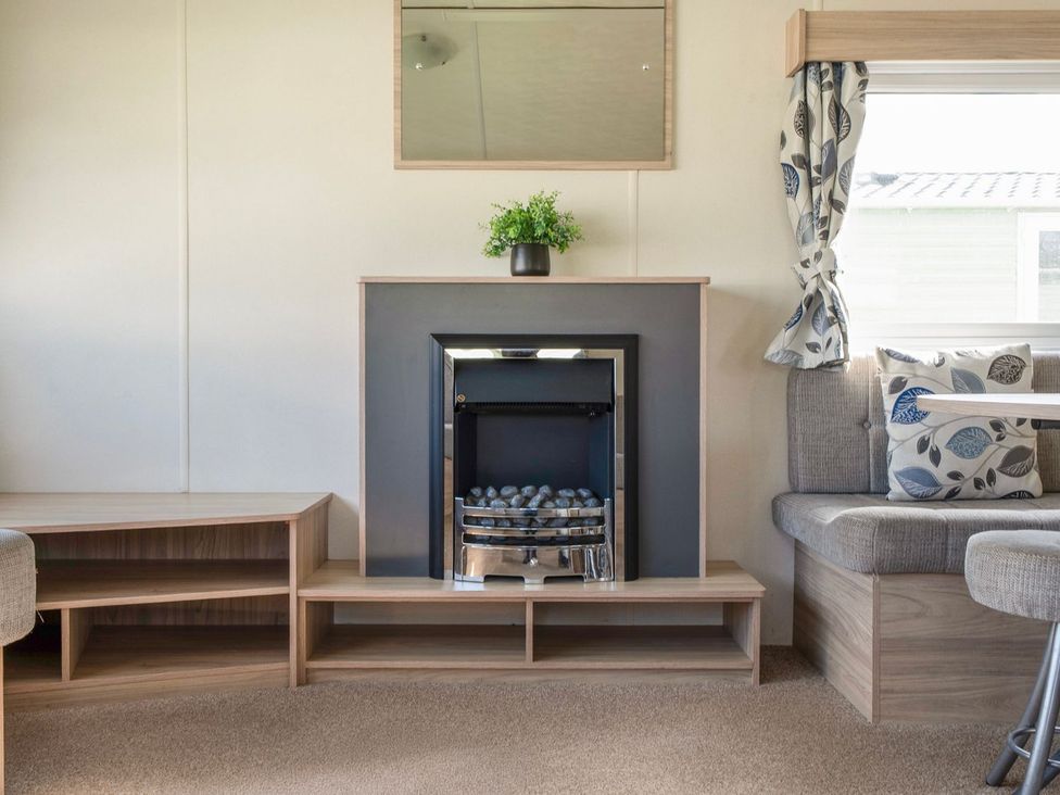 A living room with a fireplace and seating at Windsurfer’s Rest - Hayling Island