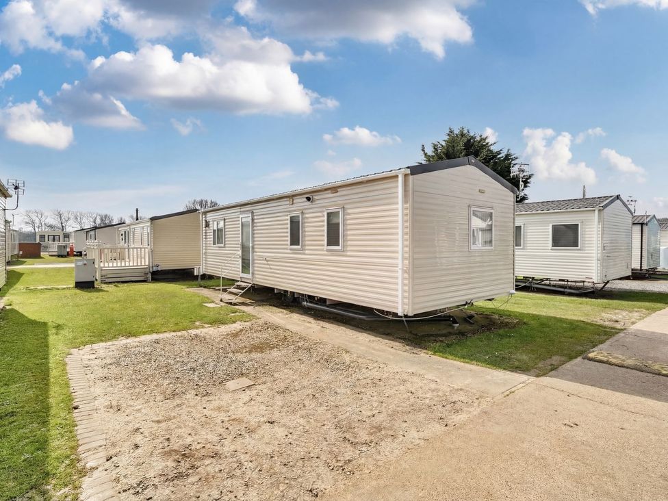 A caravan in front of a grassy area at Windsurfer’s Rest - Hayling Island
