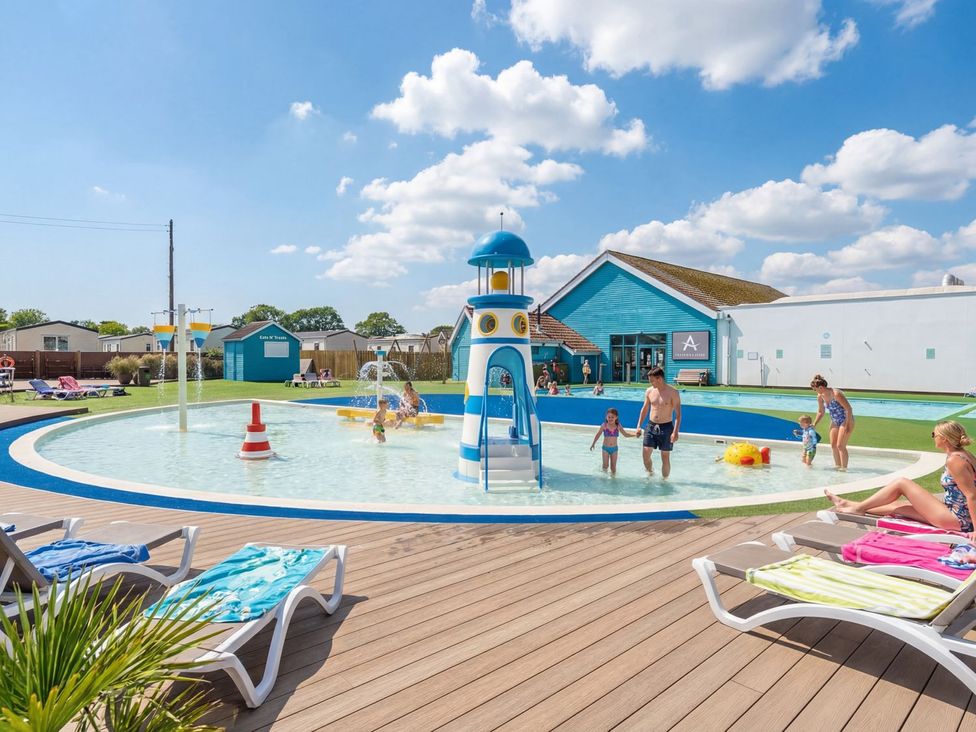 An outdoor pool area with a water slide and sun loungers at Windsurfer’s Rest - Hayling Island