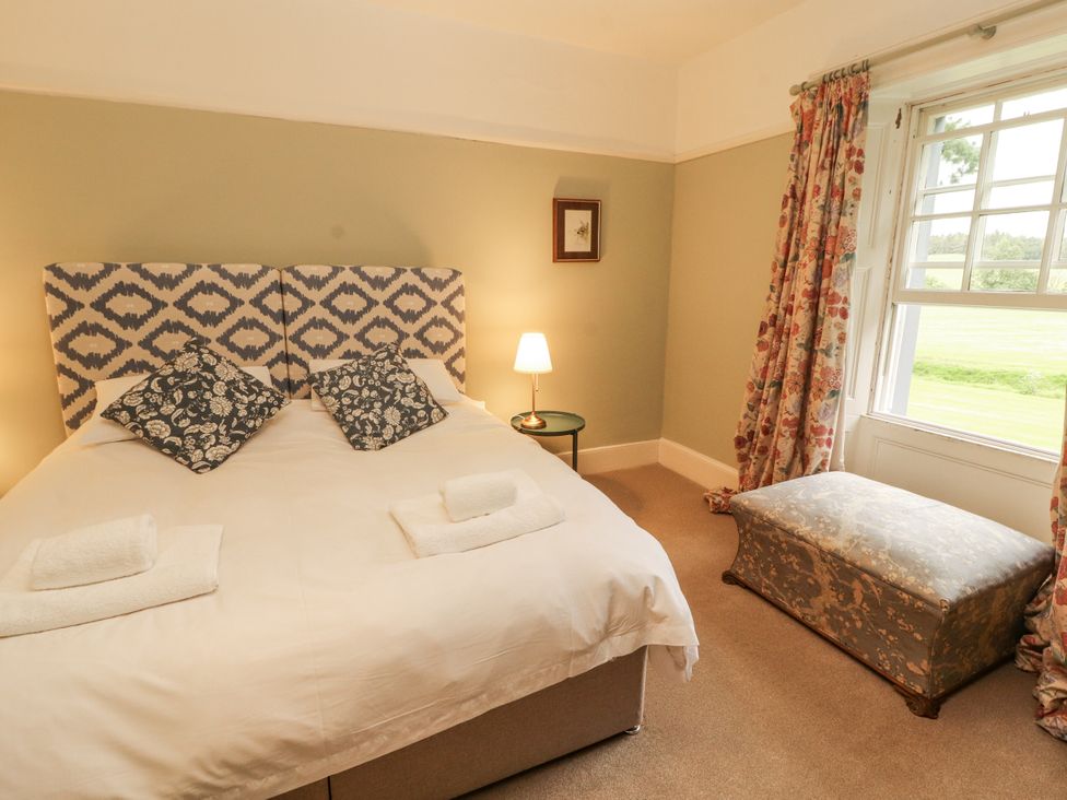 A bedroom with a bed and an ottoman at Westward Park in Westward near Wigton