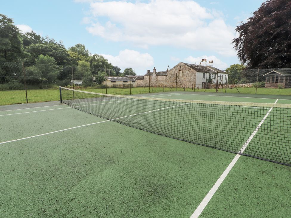 A tennis court with a net and a building in the background at Westward Park near Wigton