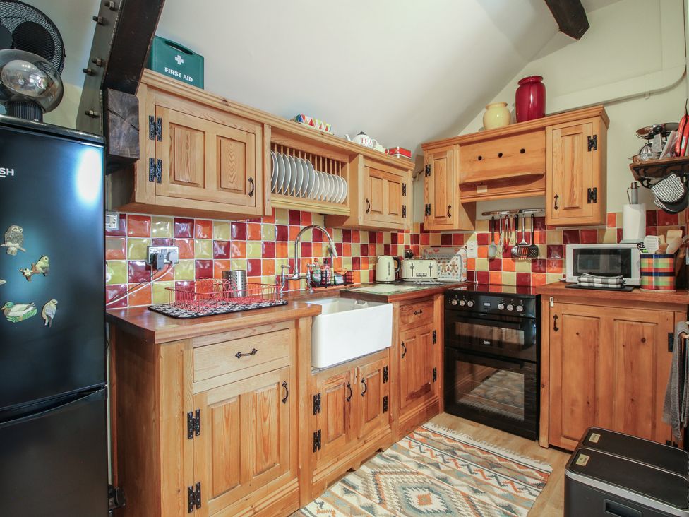 A kitchen with wooden cabinets and appliances at Heribert Cottage in Shrewsbury