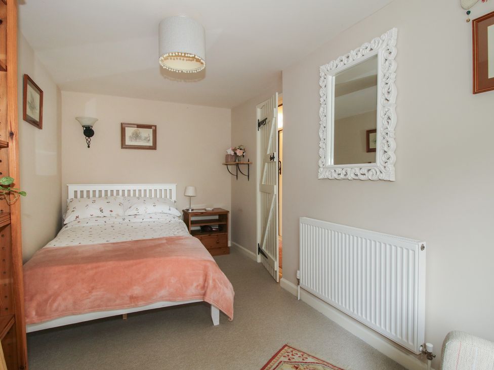 A bedroom with a bed and nightstand at Heribert Cottage in Shrewsbury