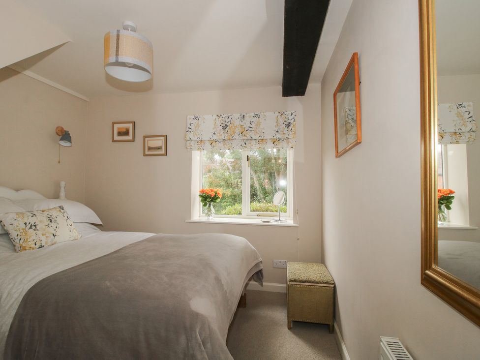 A bedroom with a bed and window at Heribert Cottage in Shrewsbury