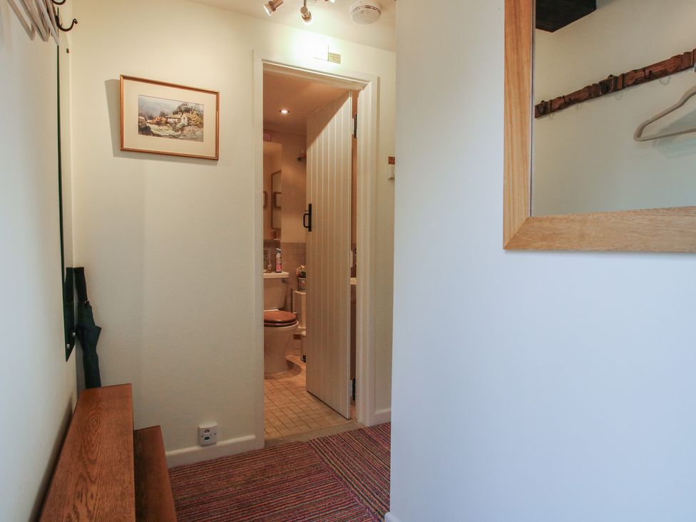 A hallway with a mirror and a bench at Heribert Cottage in Shrewsbury