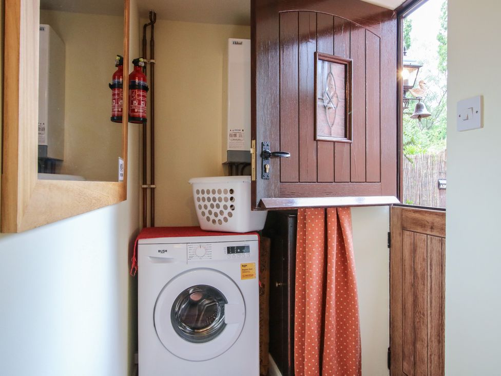 A utility room with a washing machine and fire extinguishers at Heribert Cottage in Shrewsbury