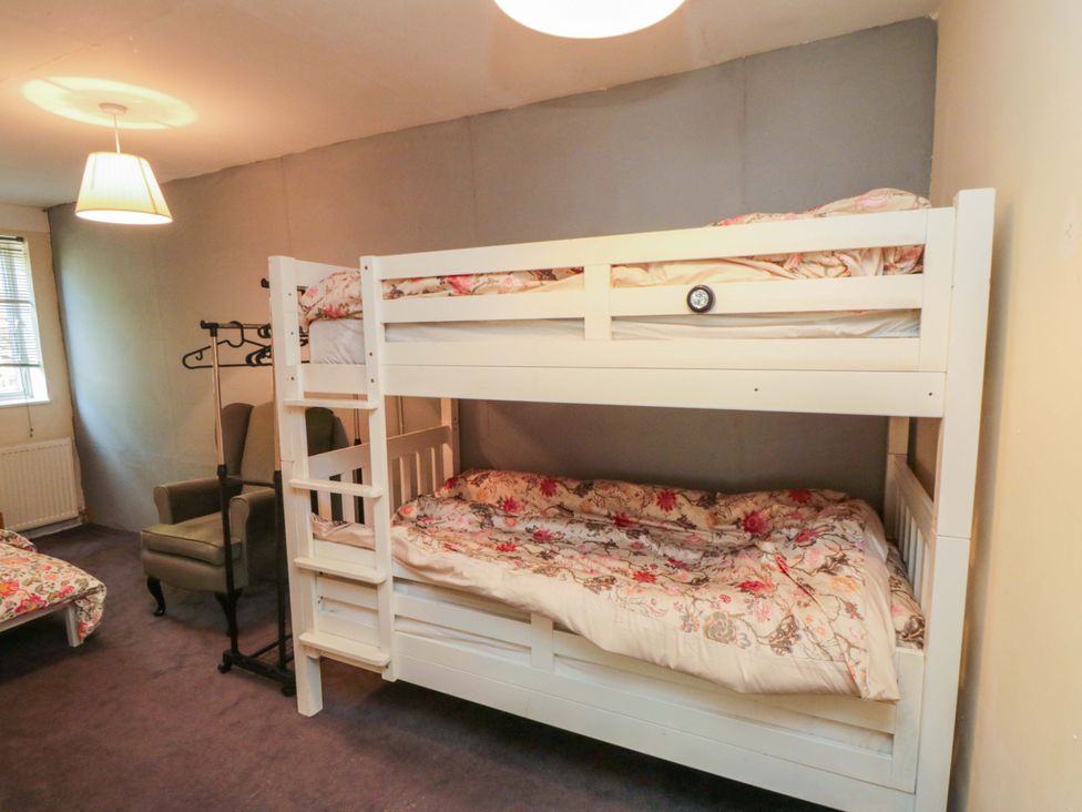 A bedroom with a bunk bed and a chair at Grove Stables House Yarm