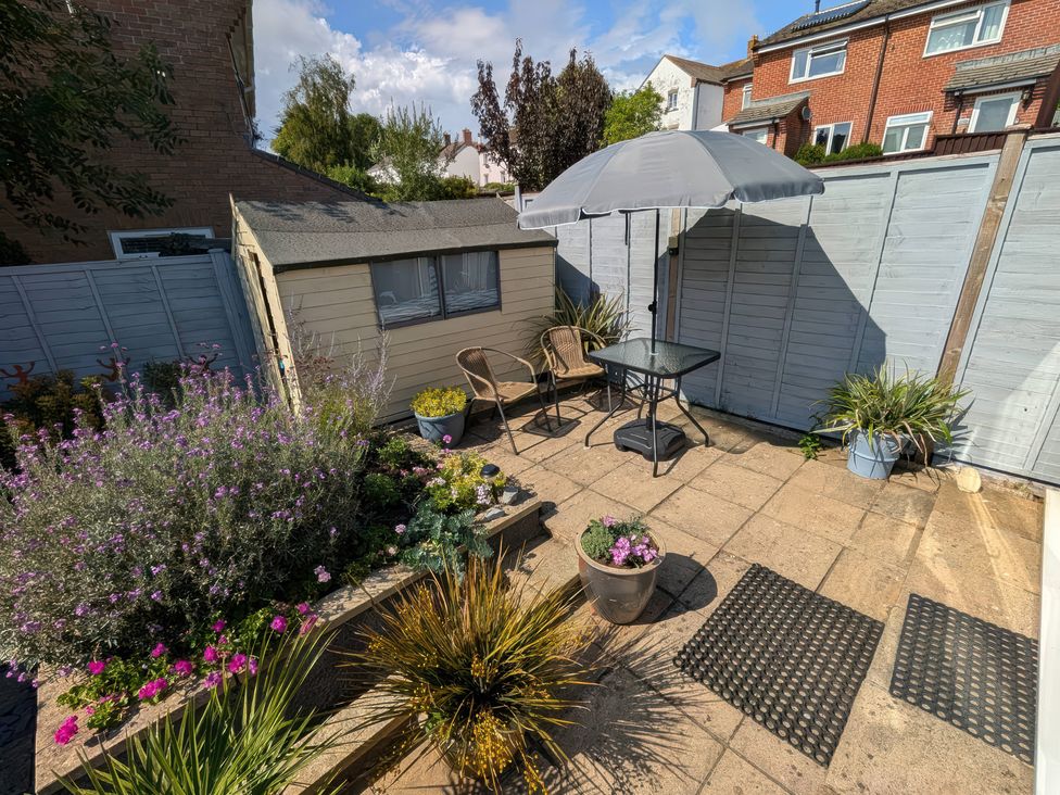 A garden with a table under an umbrella and a shed at Seahills in Lyme Regis