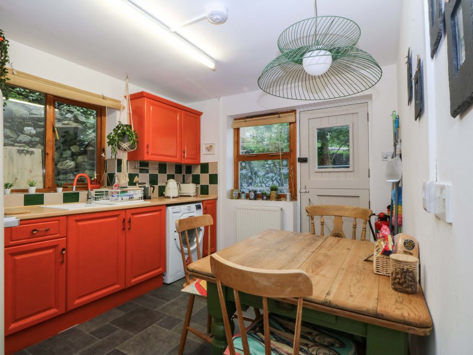 A kitchen with orange cabinets and wooden table at Waterfall Retreat in Blaenau Ffestiniog