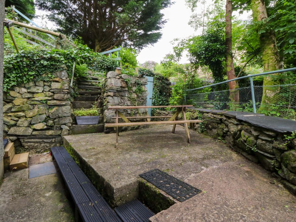 A garden area with stone walls and a table at Waterfall Retreat in Blaenau Ffestiniog