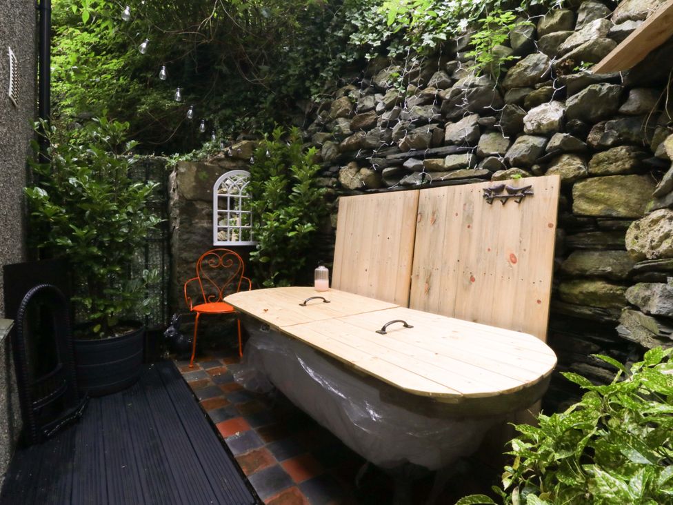 An outdoor seating area with a wooden table and a chair at Waterfall Retreat in Blaenau Ffestiniog