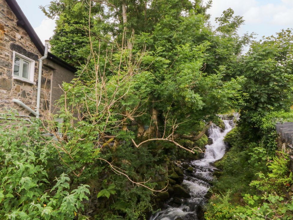 A stone house with trees and a waterfall at Waterfall Retreat in Blaenau Ffestiniog