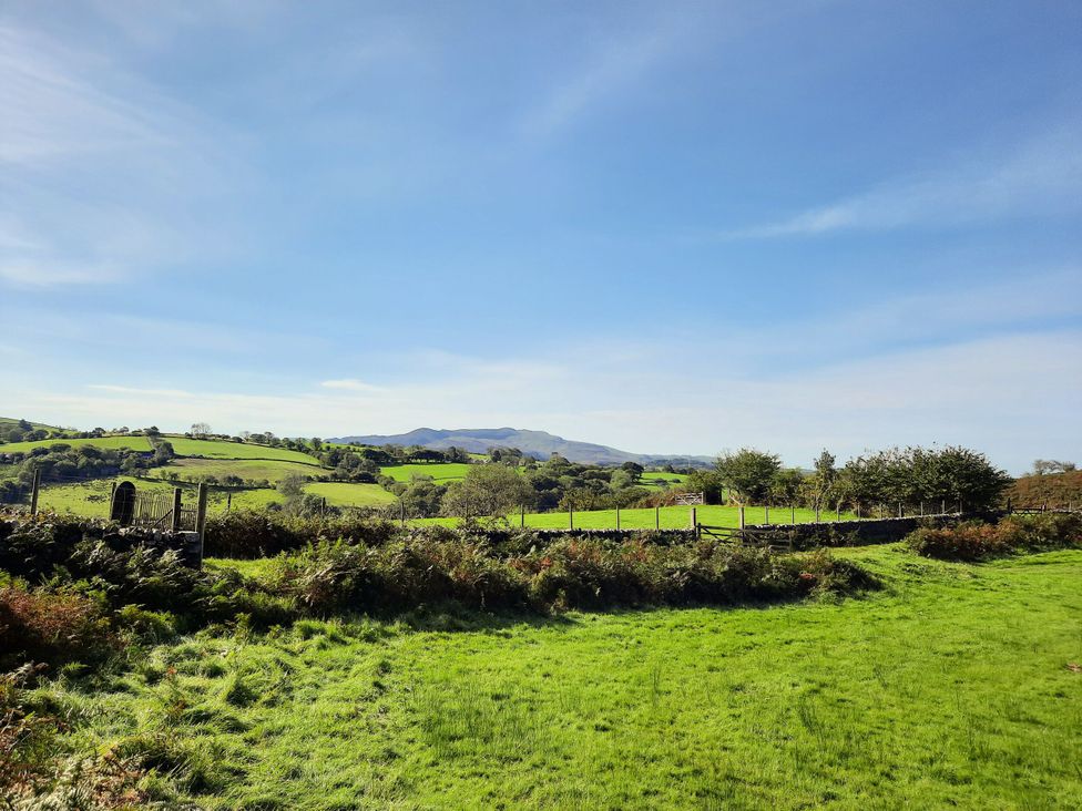 A landscape with grassy fields and a fence at Waterfall Retreat in Blaenau Ffestiniog