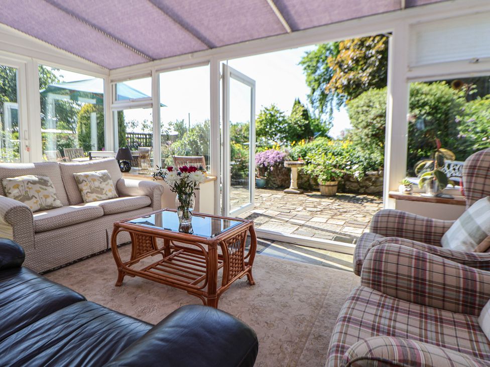 A conservatory with seating and a garden view at Cynynion Uchaf Rhydycroesau near Trefonen