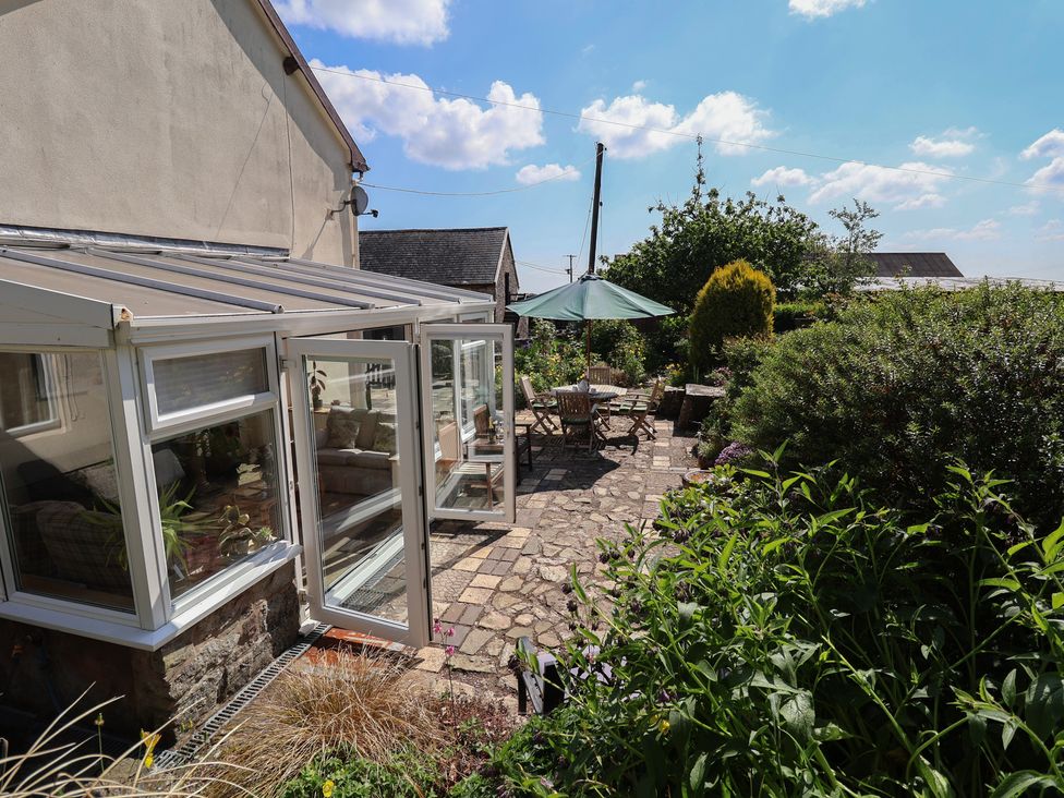 A garden with a conservatory and seating area at Cynynion Uchaf near Rhydycroesau