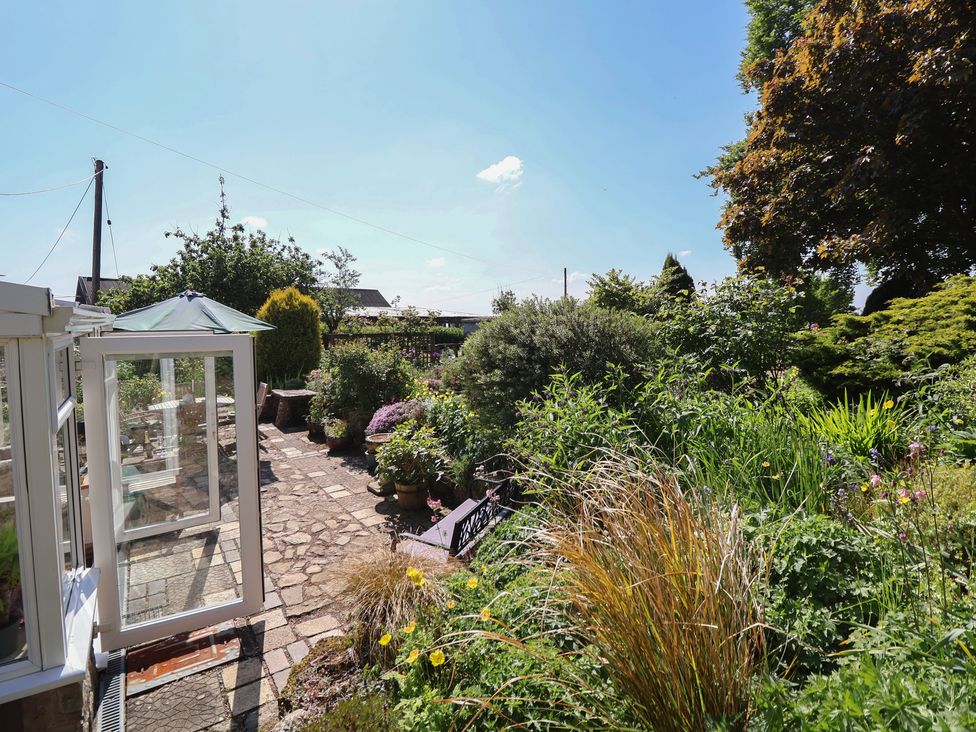 A garden with a stone pathway and various plants at Cynynion Uchaf in Rhydycroesau near Trefonen