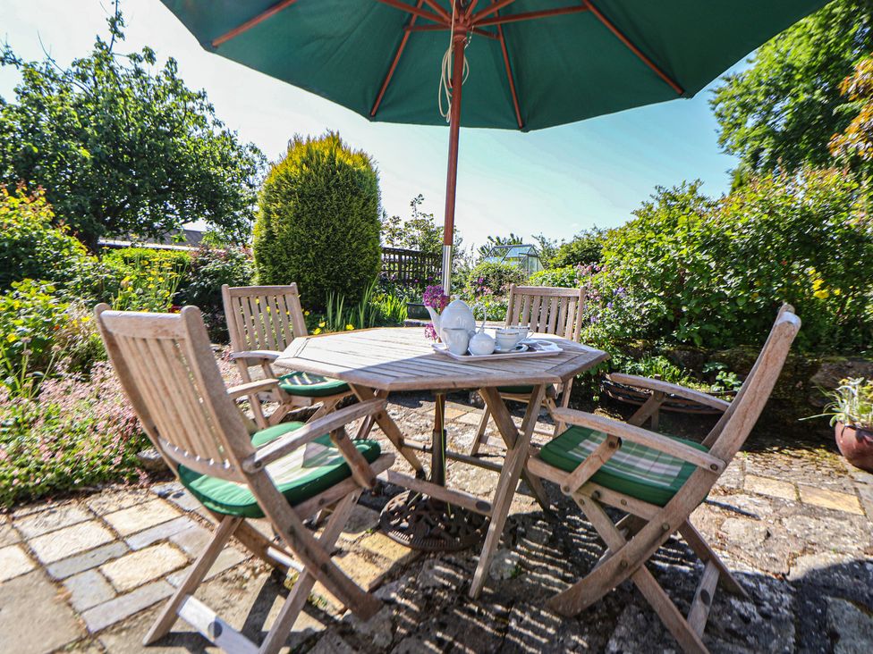 A garden with a table and chairs under an umbrella at Cynynion Uchaf in Rhydycroesau near Trefonen