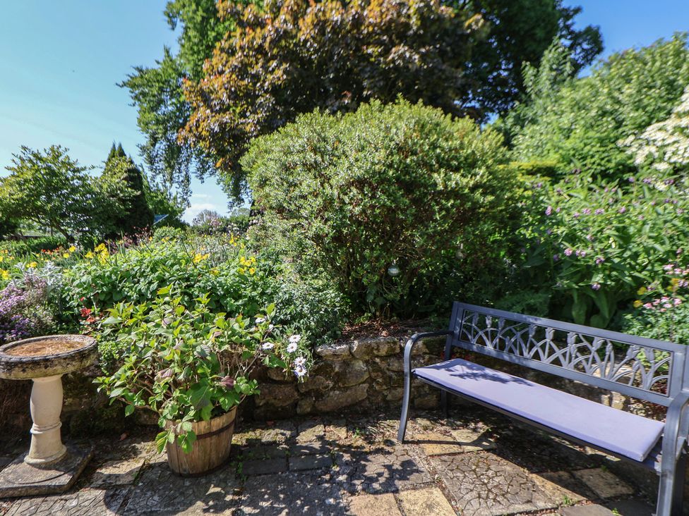 A garden with a bench, birdbath, and flowers at Cynynion Uchaf near Rhydycroesau