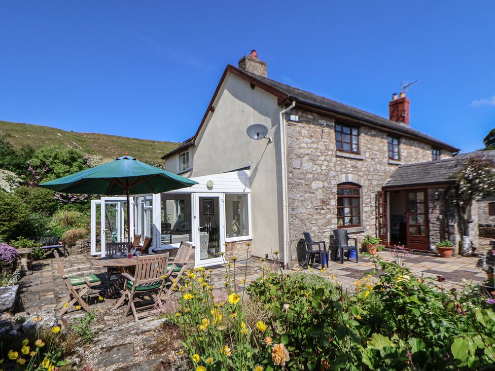 An outdoor patio area with garden plants and a table under an umbrella at Cynynion Uchaf Rhydycroesau near Trefonen