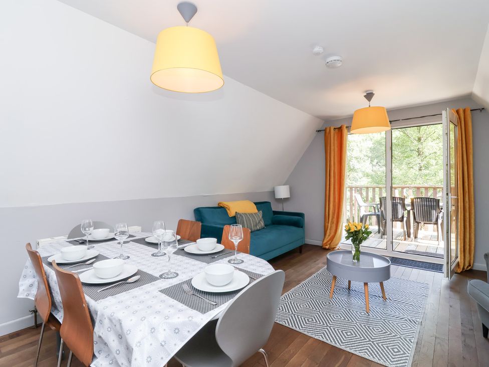 A dining area with a table set for meals and a sofa at Valley Lodge 37, St Ann's Chapel, Cornwall