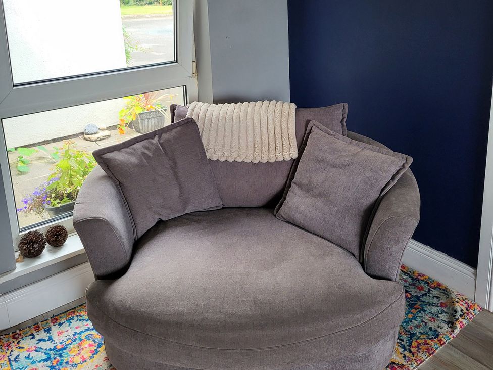 A chair with cushions and a blanket by a window at Beech Lodge in Foulksmills, County Wexford