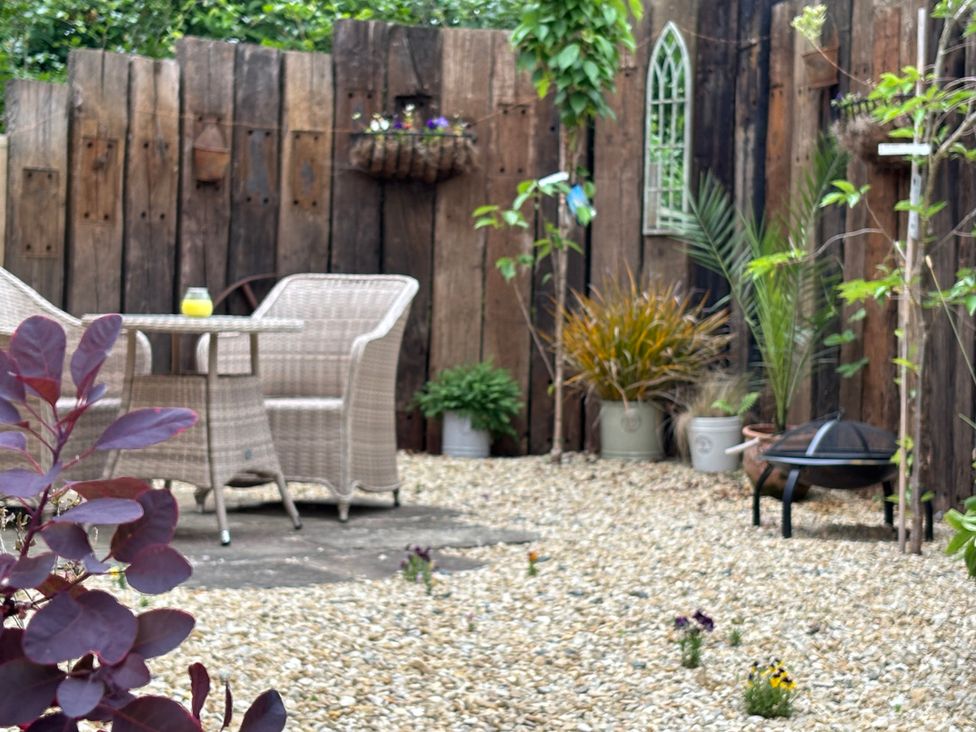 A garden with table and chairs surrounded by gravel and plants at Pheasants Rise Apartment in Ross-On-Wye