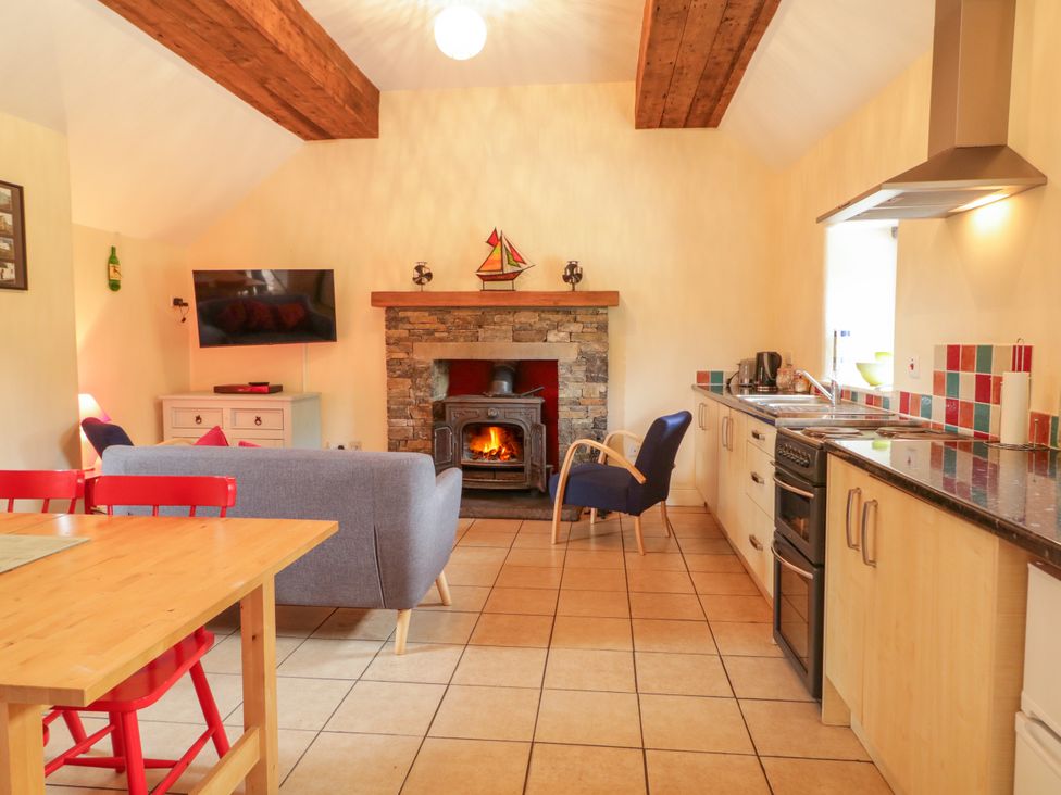 A living room with a fireplace and kitchen area at Shane's Cottage in Falcarragh, County Donegal