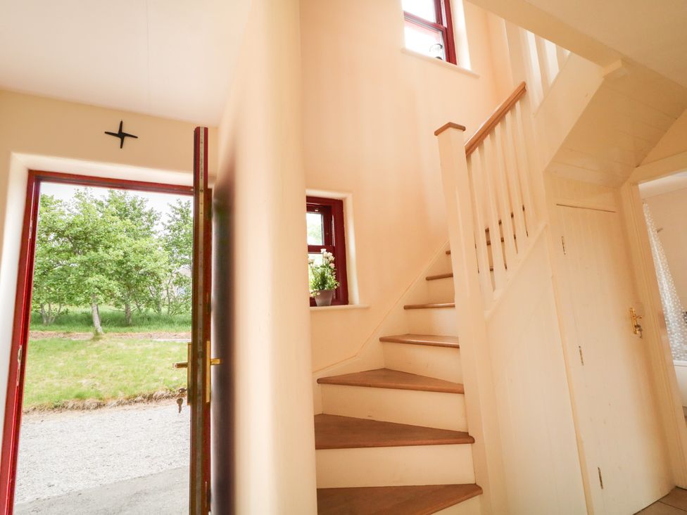 A hallway with a staircase and a front door at Shane's Cottage, Falcarragh, County Donegal
