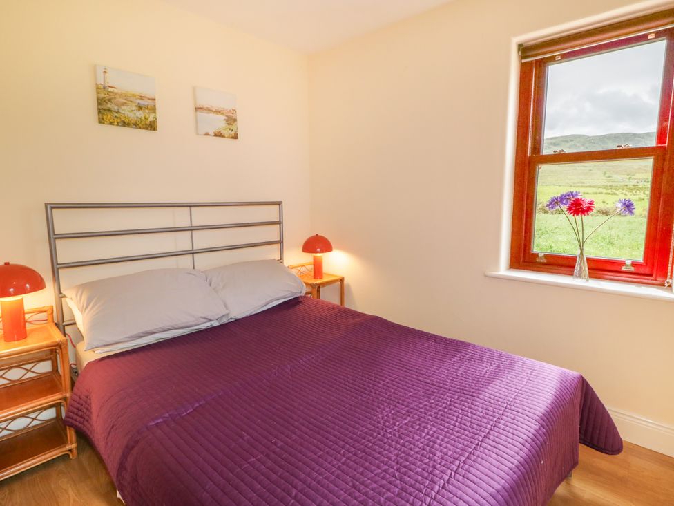 A bedroom with a bed and two lamps at Shane's Cottage in Falcarragh, County Donegal